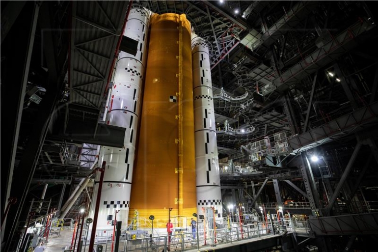 Slika materijala koju je stavila na raspolaganje Nacionalna uprava za aeronautiku i svemir (NASA) prikazuje jezgru Space Launch System (SLS) na vrhu mobilnog lansera unutar High Bay 3 zgrade za sklapanje vozila u NASA-inom svemirskom centru Kennedy (KSC) na Floridi, SAD , 12. lipnja 2021. (izdano 16. lipnja 2021.). Timovi s NASA-inim Exploration Ground Systems i izvođačem Jacobsom podigli su i spustili jezgreni stupanj - najveći dio rakete - na mobilni lanser, postavljajući ga između dva čvrsta raketna pojačivača. Jezgra od 188.000 funti, sa svoja četiri RS-25 motora, pružit će više od dva milijuna funti potiska tijekom lansiranja i izrona, a zajedno s pojačivačima, pružit će više od 8,8 milijuna funti potiska za slanje misije Artemis I. u svemir. U okviru programa Artemis, NASA će poslati prvu ženu i prvu obojenu osobu na Mjesec, kao i uspostaviti održivu prisutnost na površini Mjeseca u pripremi za ljudske misije na Mars. EPA/NASA/CORY HUSTON HANDOUT